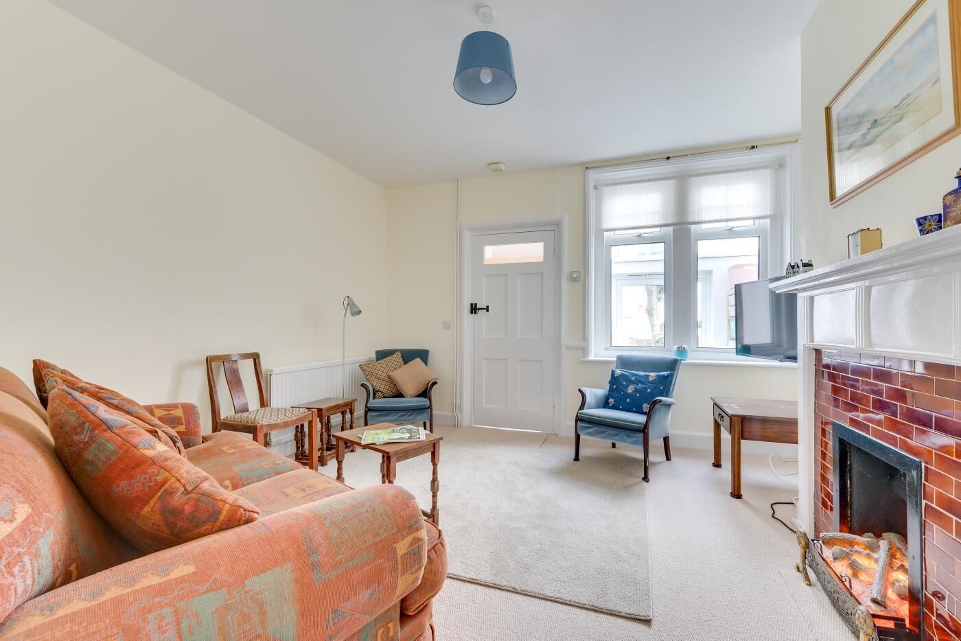 Ein Wohnzimmer mit einer Couch, Sesseln, einem Couchtisch, einem Kamin und einem Fernseher.