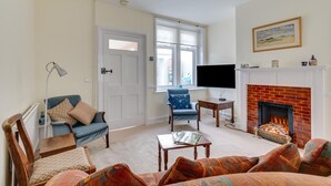 A living room with a fireplace, a television, and a window with blinds. - 3 Bed in Littlestone (oc-bt009) (Littlestone)