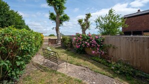 A garden with a bench, trees, and a wooden fence. - 3 Bed in Littlestone (oc-bt009) (Littlestone)