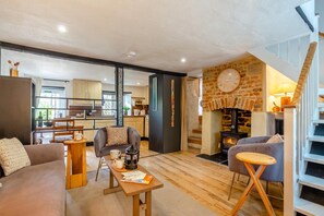Una sala de estar moderna con chimenea, un sofá, una mesa de centro y un comedor con una cocina al fondo.