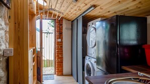 A compact kitchen with a washing machine, a refrigerator, and a wooden ceiling. - 3 Bed in Eype (oc-e34183) (Eype)