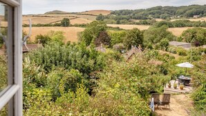 A rural landscape with rolling hills, a variety of vegetation, and scattered buildings. - 3 Bed in Eype (oc-e34183) (Eype)