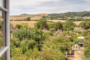 A rural landscape with rolling hills, a variety of vegetation, and scattered buildings. - 3 Bed in Eype (oc-e34183) (Eype)