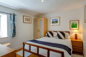 A bedroom with a bed, bedside tables, a wardrobe, and a window with curtains. - 3 Bed in Eype (oc-e34183) (Eype)