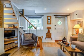 Uma sala de estar moderna com escada, televisão de tela plana, sofá de couro, mesa de centro e área de jantar.