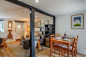 Un coin repas avec une table et des chaises en bois, une bibliothèque et un tableau encadré au mur.