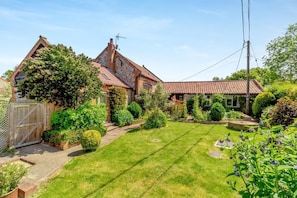 A residential property with a well-maintained lawn, a wooden gate, and a brick house with a tiled roof. - 3 Bed in Sustead (oc-1880) (Sustead)