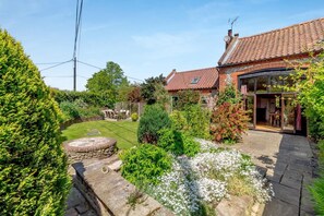 A house with a garden, a stone wall, and a patio area.