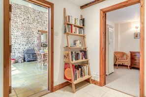 A room with a wooden bookshelf, a stone wall, a fireplace, and a dining area. - 3 Bed in Sustead (oc-1880) (Sustead)