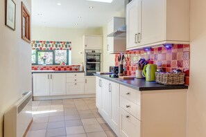 A modern kitchen with white cabinets, a tiled backsplash, and a window with a view of greenery.