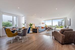 Ein modernes Wohnzimmer mit Essbereich, großen Fenstern und Blick ins Freie.