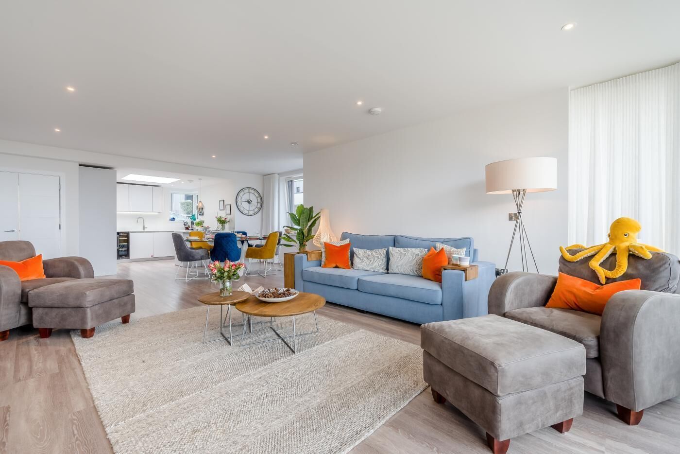 A modern living room with a blue sofa, grey armchairs, and a coffee table.