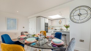 Un'elegante zona pranzo con un tavolo rotondo in vetro, diverse sedie e un grande orologio a parete.