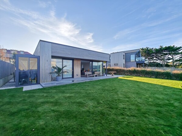 A modern house with a large lawn, a patio, and a glass-enclosed room. - 3 Bed in Constantine Bay (oc-t34218) (Constantine Bay)