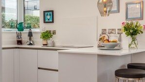 Una cucina moderna con isola centrale, sgabelli da bar, una finestra con vista e diversi utensili da cucina.