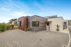 Ein modernes Wohngebäude mit gepflasterter Auffahrt, einem kleinen Garten und blauem Himmel.