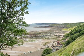 A coastal landscape with a beach, a curved pathway, and a building with a red roof. - 2 Bed in Scarborough (oc-s016) (Scarborough)