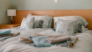 A bed with multiple pillows and folded blankets, a bedside lamp, and a wooden headboard. - 2 Bed in Scarborough (oc-s016) (Scarborough)