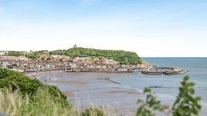 A coastal town with a historic castle on a hill, a sandy beach, and a harbor with boats. - 2 Bed in Scarborough (oc-s016) (Scarborough)