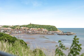 A coastal town with a historic castle on a hill, a sandy beach, and a harbor with boats. - 2 Bed in Scarborough (oc-s016) (Scarborough)