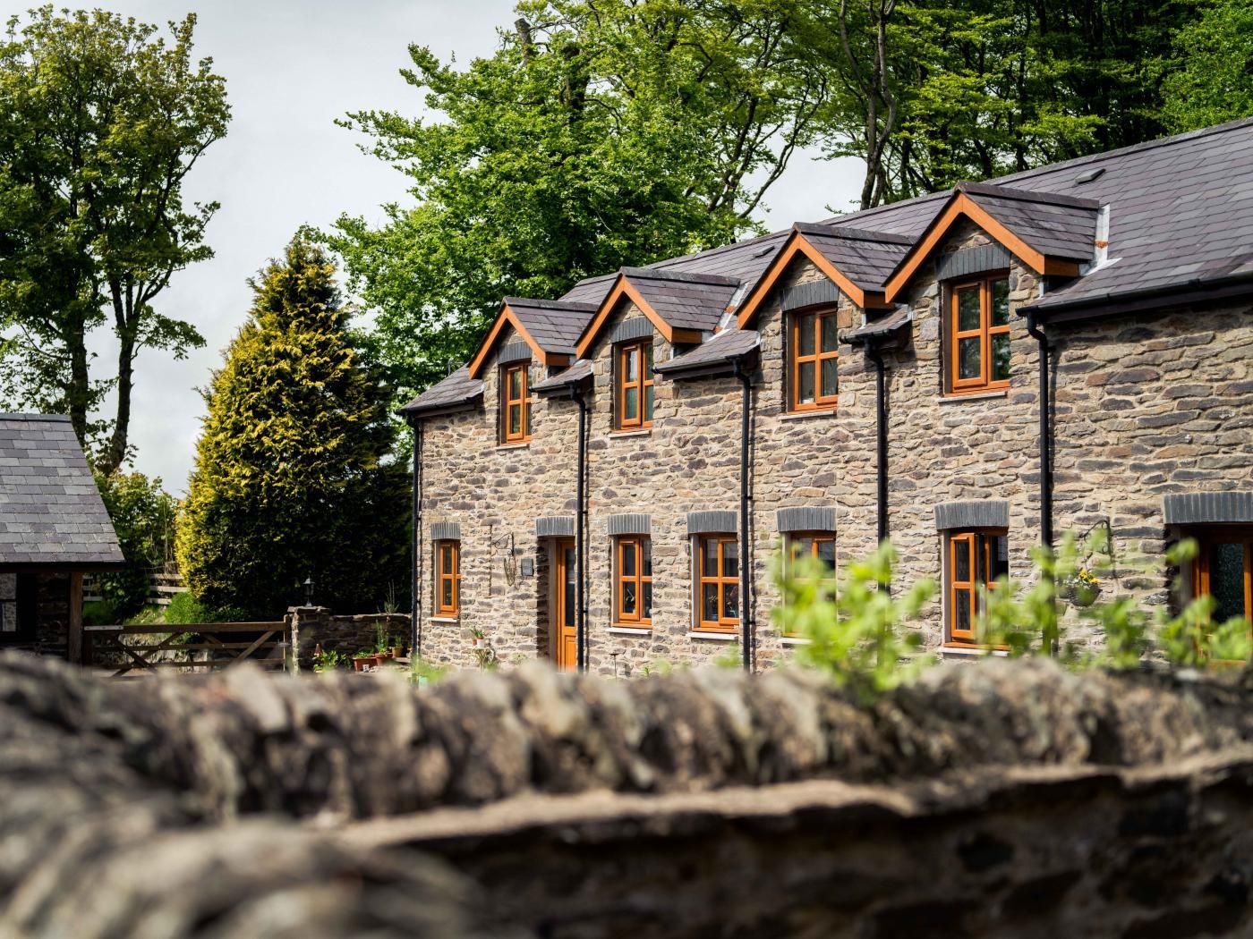 A stone building with multiple windows and a sloped roof.