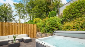 A hot tub, outdoor seating, and a wooden fence in a garden setting. - 3 Bed in Aberaeron (oc-bow315) (Bethania)