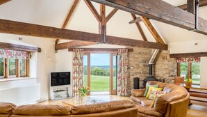 Una sala de estar acogedora con chimenea de piedra, sofás de cuero y televisor.