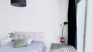 A bedroom with a bed, bedside table, lamp, potted plant, and a view of the outside. - Nordic Home Bliss With Music Moments (Helsinki)