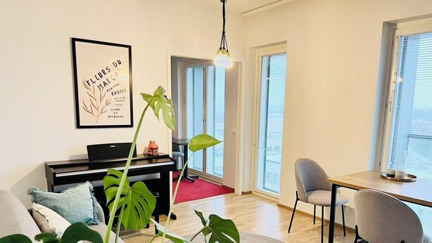 A living room with a piano, a dining table with chairs, large windows, and a framed picture on the wall. - Nordic Home Bliss With Music Moments (Helsinki)