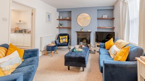 A living room with two blue sofas, a round mirror, and a fireplace. - 2 Bed in Tenby (oc-pw1031) (Tenby)