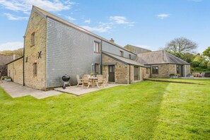 A stone house with a patio, outdoor seating, and a barbecue. - 3 Bed in Wadebridge (oc-m34228) (Saint Issey)
