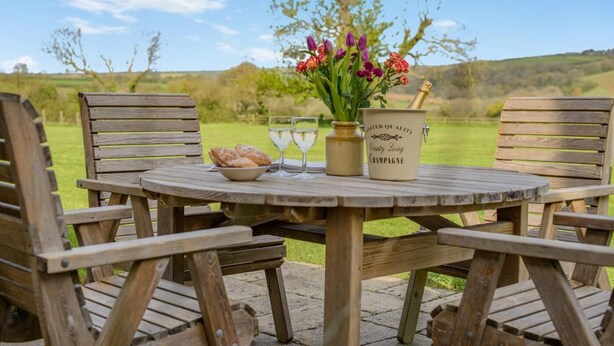 Ein Holztisch mit einer Champagnerflasche, einer Schale Gebäck und einer Blumenvase.