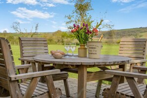 A wooden table with a bottle of champagne, a bowl of pastries, and a vase of flowers. - 2 Bed in Wadebridge (oc-t34229) (Saint Issey)