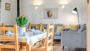 Ein Essbereich mit einem Tisch für vier Personen, einem grauen Sofa und einem Bullenbild an der Wand.