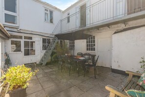 A patio area with a table and chairs, a staircase, and a garden. - 5 Bed in Mousehole (oc-kellan) (Mousehole)