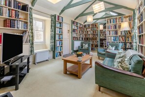 A cozy living room with a flat-screen TV, a wooden coffee table, and a green sofa. - 5 Bed in Mousehole (oc-kellan) (Mousehole)