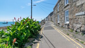 Une rue étroite bordée d’immeubles en pierre, un ciel dégagé et un bateau sur l’eau.