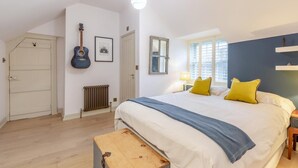 Ein Schlafzimmer mit Bett, Gitarre, Heizkörper, Fenster und Tür.