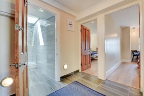 A hallway with a glass shower door, a wooden door, and a bed in the background. - 2 Bed in Barmouth (oc-bow52) (Llanaber)