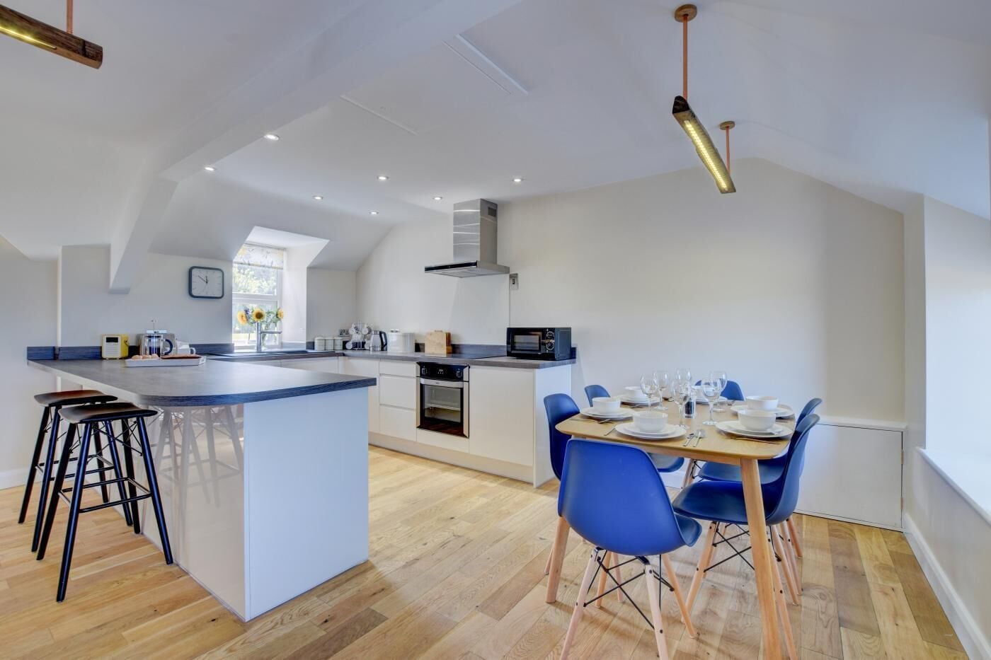 Une cuisine moderne avec un îlot central, des chaises bleues et une table à manger pour quatre personnes.