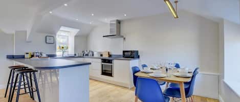 Une cuisine moderne avec un îlot central, des chaises bleues et une table à manger pour quatre personnes.