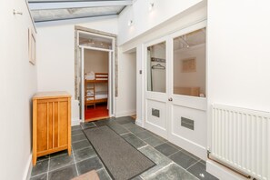 Ein schmaler Korridor mit einem Holzschrank, einem Etagenbett und einer Heizung.