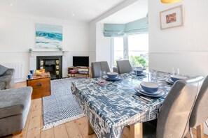 A modern living room with a dining area, fireplace, and large windows. - 4 Bed in St. Ives (oc-brhous) (St Ives)