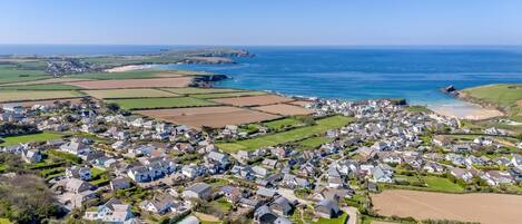A coastal village with houses, fields, and the sea.