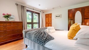 A bedroom with a bed, a wooden dresser, a window with curtains, and a door. - 2 Bed in Tresarrett (oc-b34255) (Blisland)
