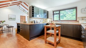 A modern kitchen with dark cabinets, a wooden island, and a large window. - 2 Bed in Tresarrett (oc-b34255) (Blisland)