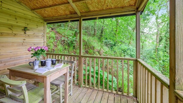 A wooden deck with a table and chairs, a coffee maker, and a vase of flowers. - 2 Bed in Tresarrett (oc-b34255) (Blisland)