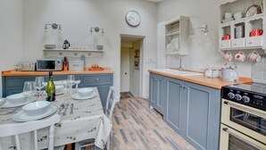 A kitchen with a dining table set, a microwave, a kettle, and a clock on the wall. - 2 Bed in Knapton (oc-1883) (Knapton)