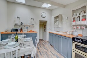 A kitchen with a dining table set, a microwave, a kettle, and a clock on the wall. - 2 Bed in Knapton (oc-1883) (Knapton)