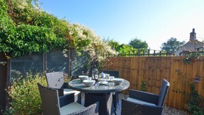 A round table with four wicker chairs, a small vase with flowers, and a teapot on the table. - 2 Bed in Knapton (oc-1883) (Knapton)